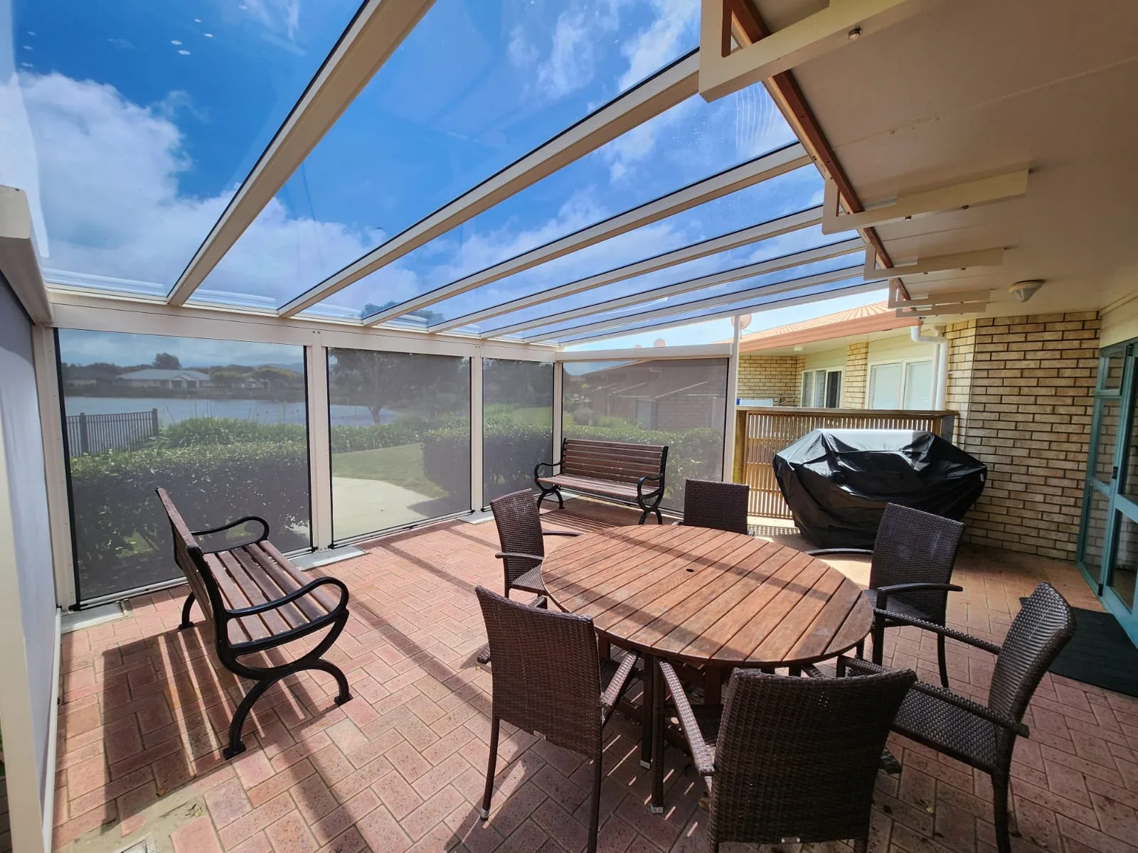 Acrylic roof over a patio with outdoor blinds fitted down one side, closing the space in