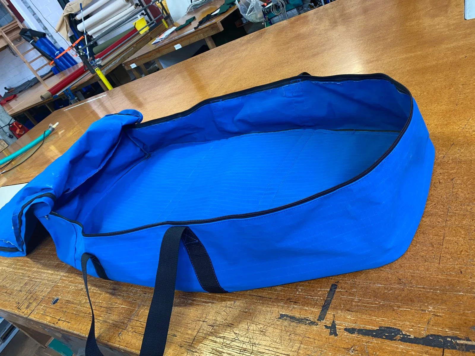 A long blue bag with its zip opened round the top so the top folds right back