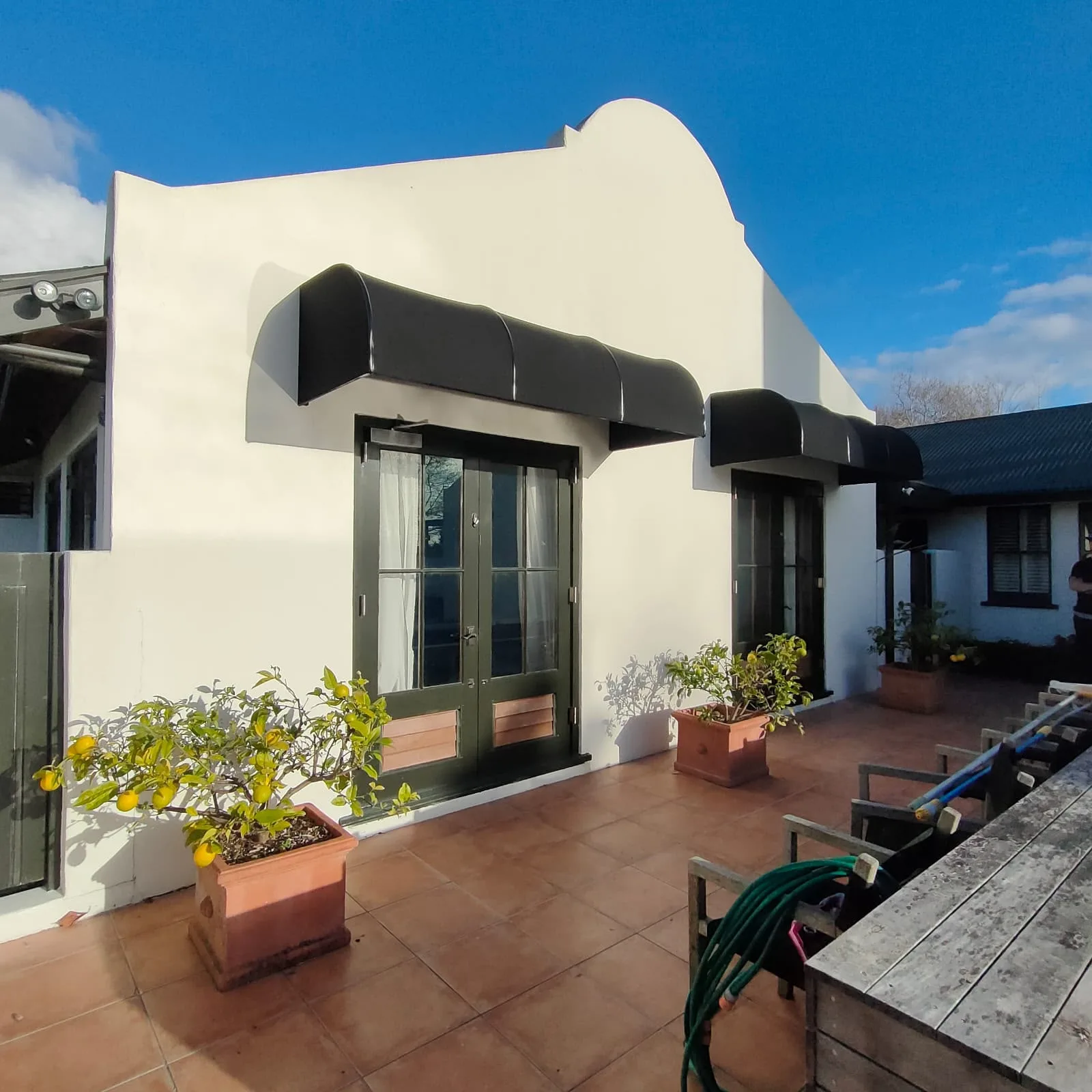 Black fixed frame awnings over the doors and windows of a white plastered home