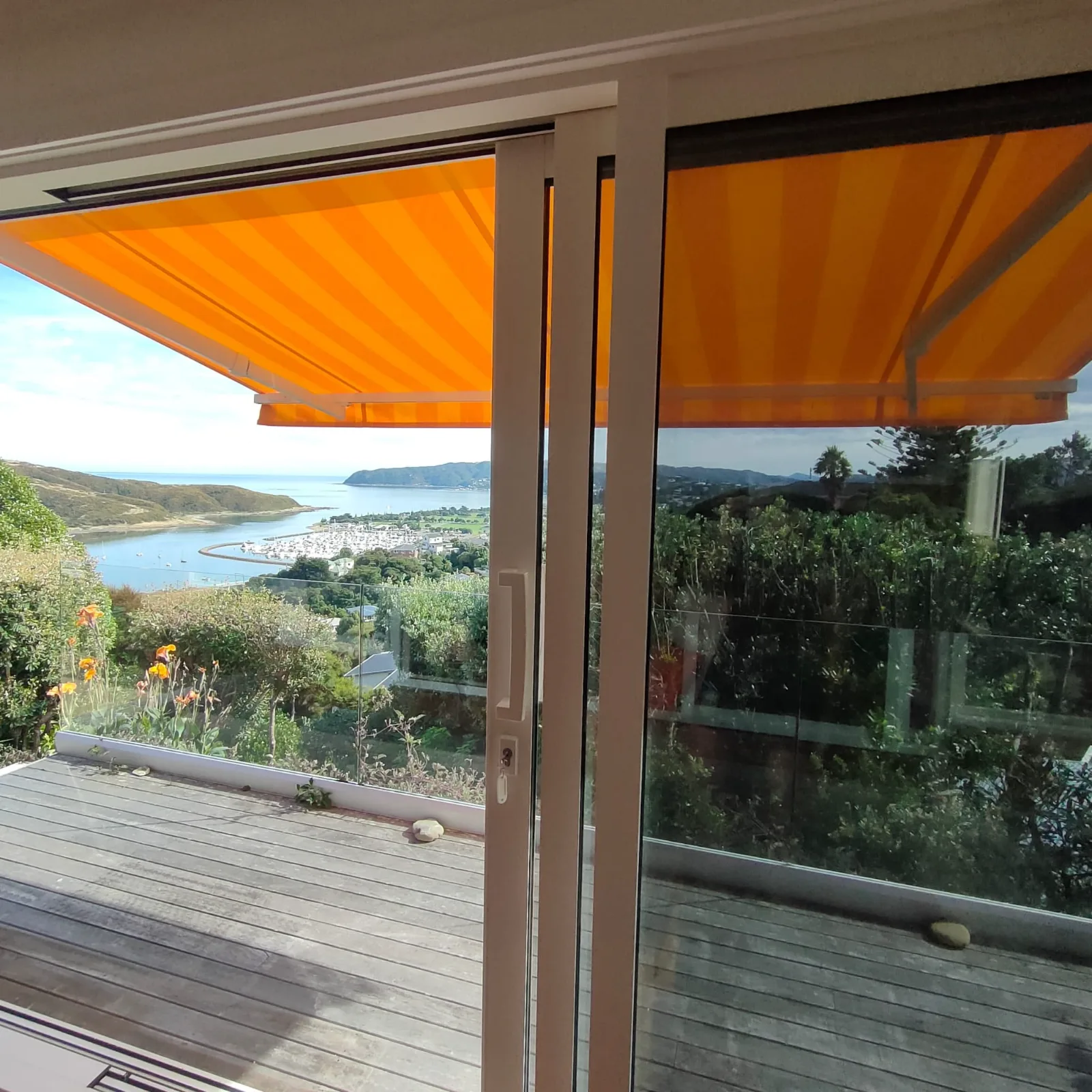Orange lateral arm awning extended over a deck looking out to an estuary