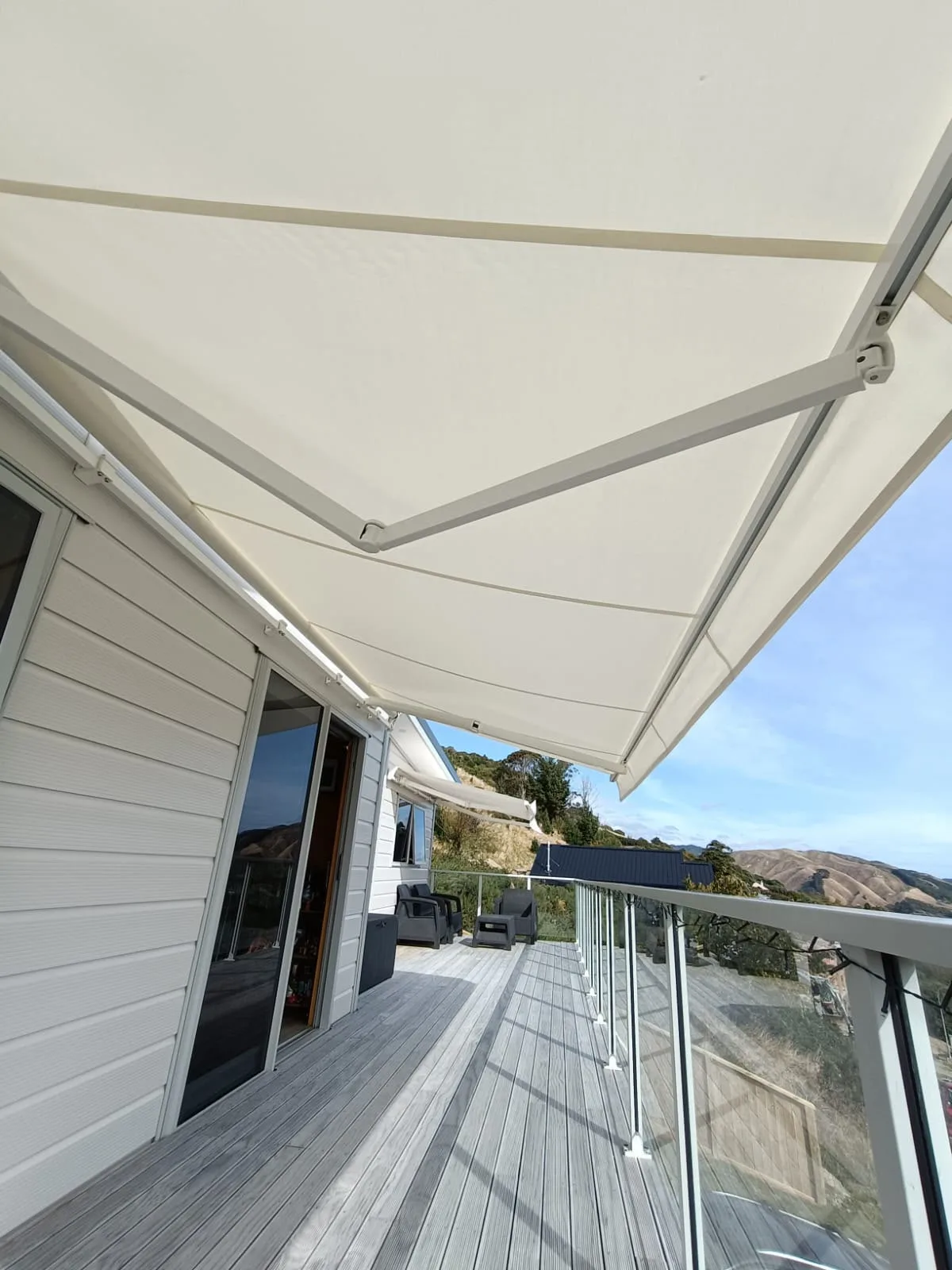 Cream lateral arm awning extended over a deck, seen from below