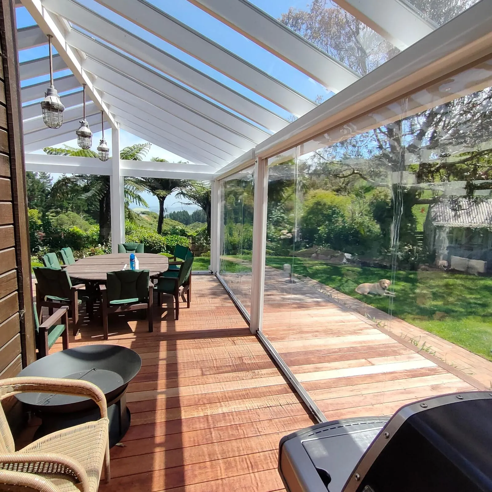 Acrylic roof running the length of a deck, with clear screens down one side and the garden beyond