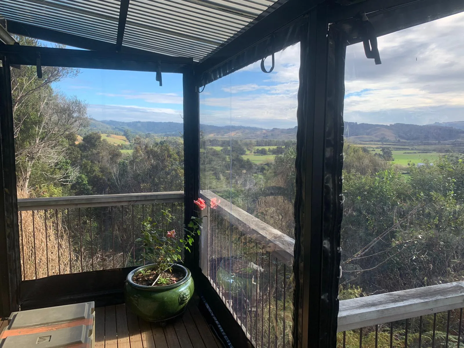 Clear PVC blinds round a deck corner, with farmland and hills beyond
