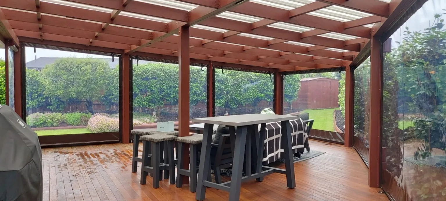Clear PVC screens closing in a timber pergola over a deck on a wet day