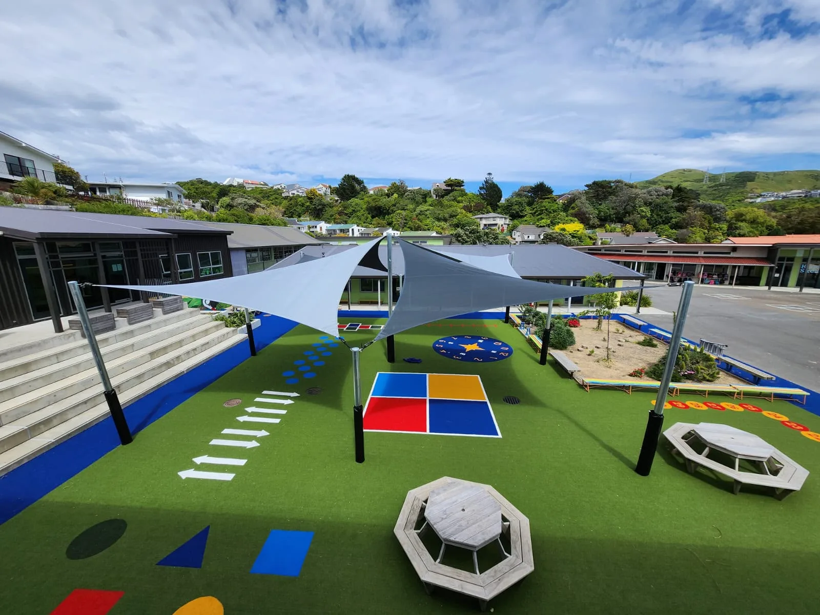 Two large shade sails covering a school's play area, sandpit and climbing equipment