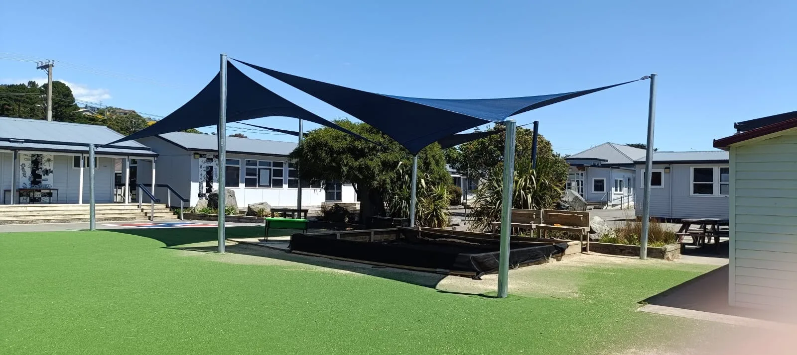 Navy shade sails over a school sandpit and seating