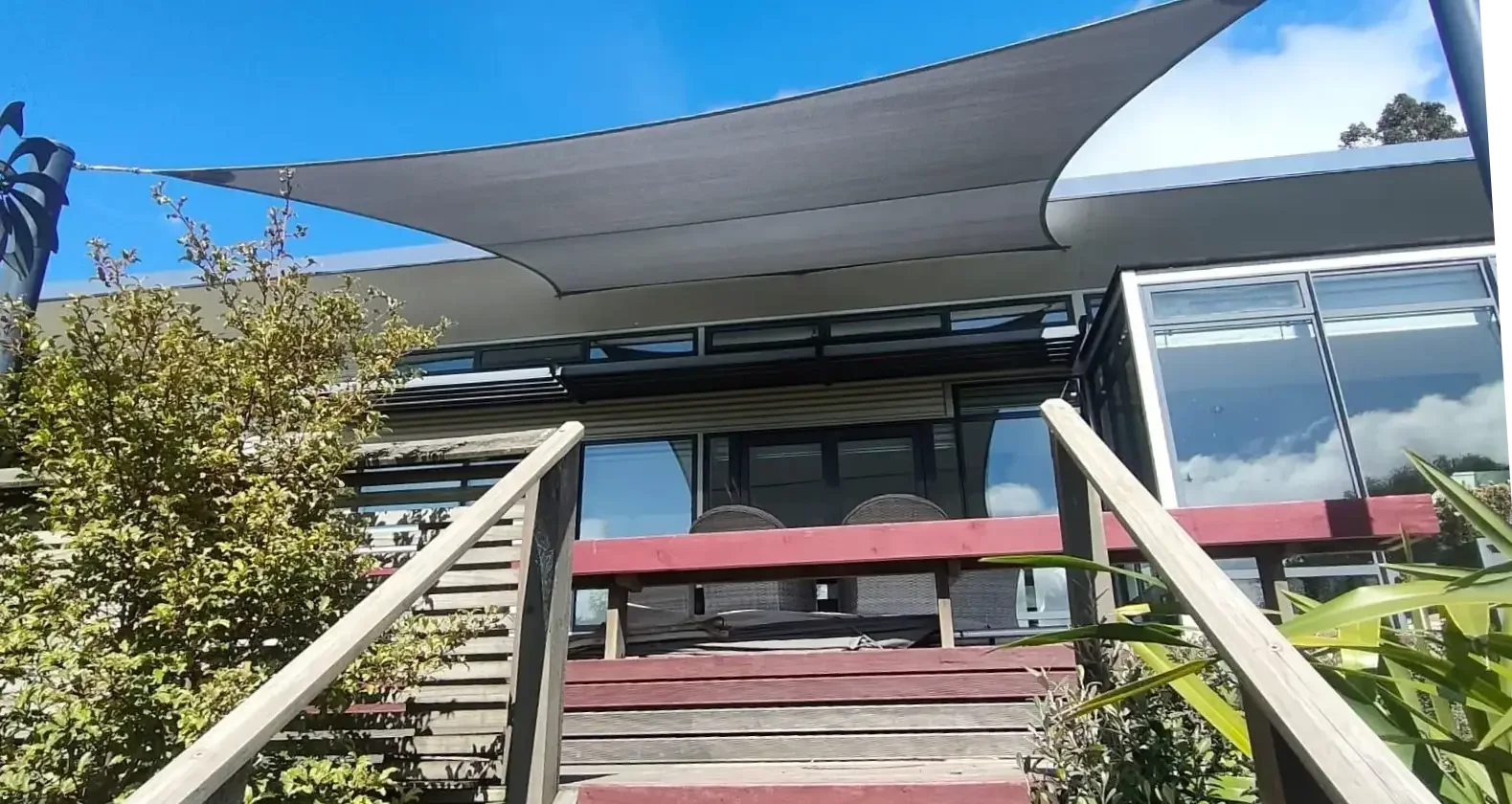 Red shade sail extended over a home's outdoor patio