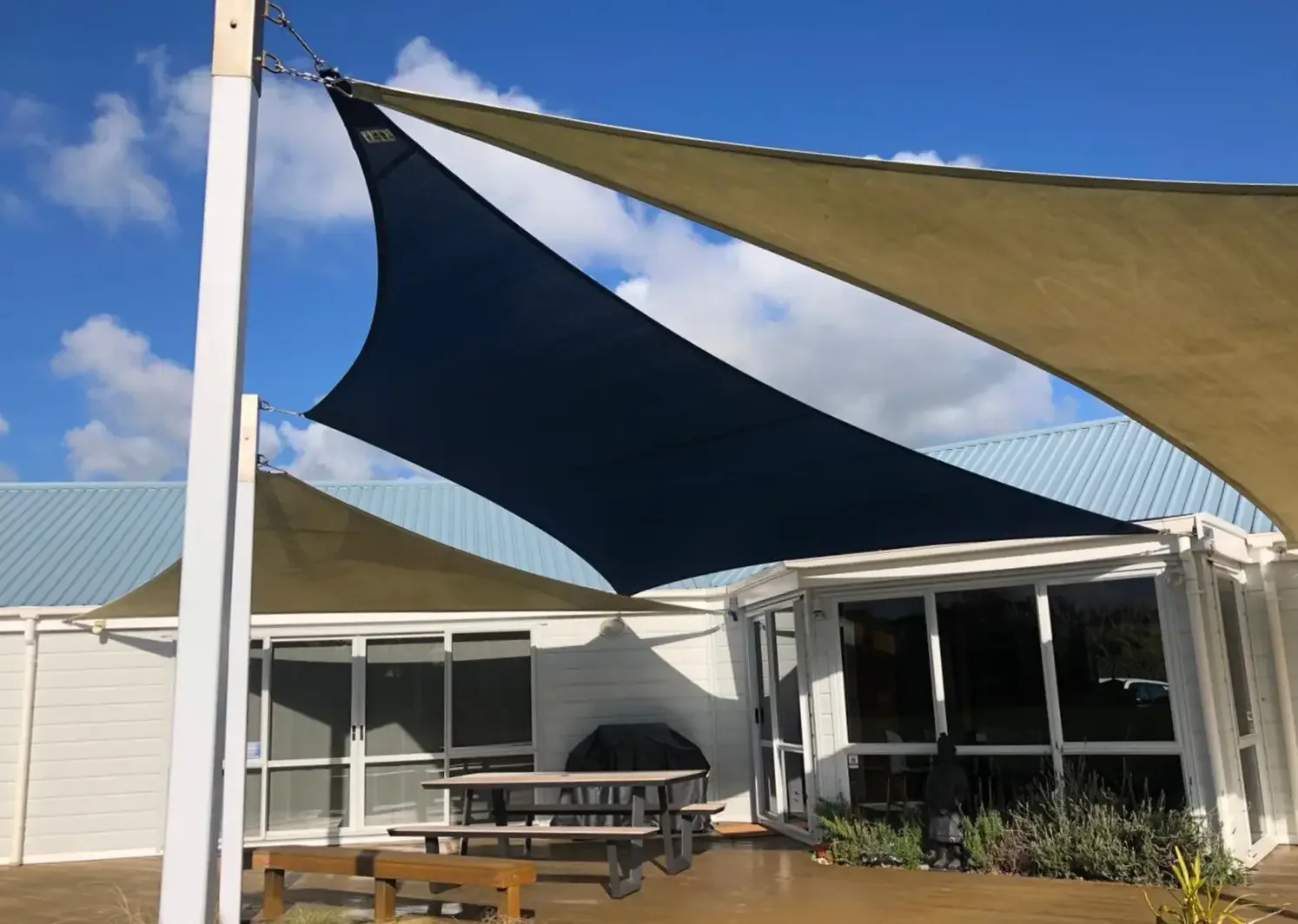 Navy blue triangular shade sail against a bright sky