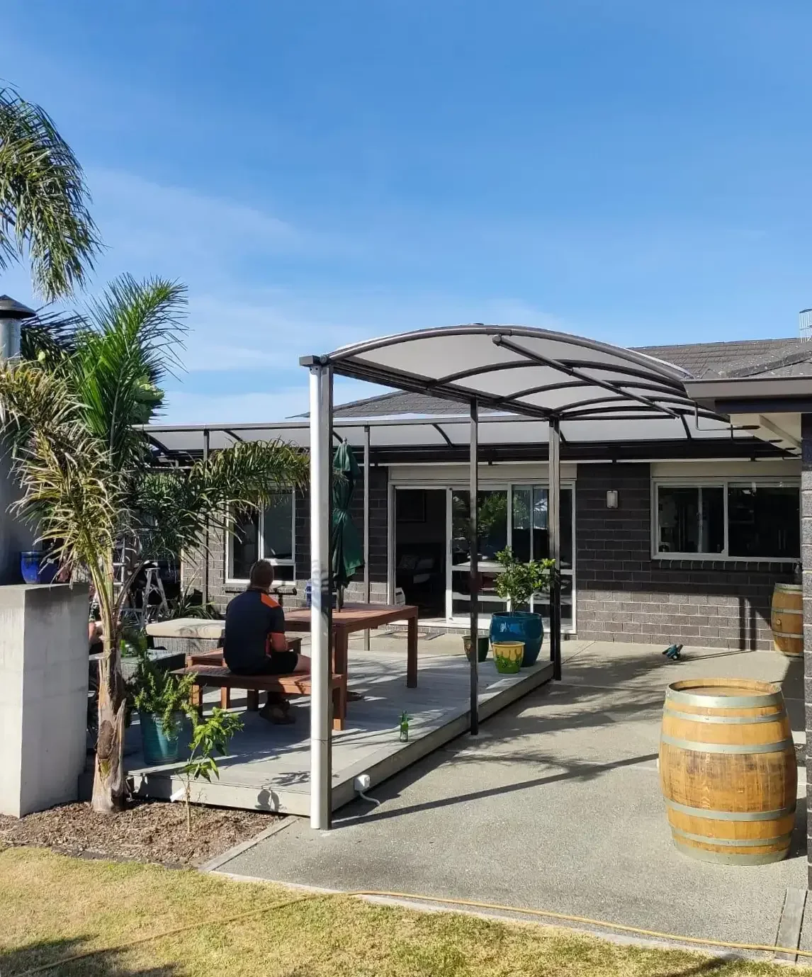 Curved tension canopy over a residential deck and outdoor dining table