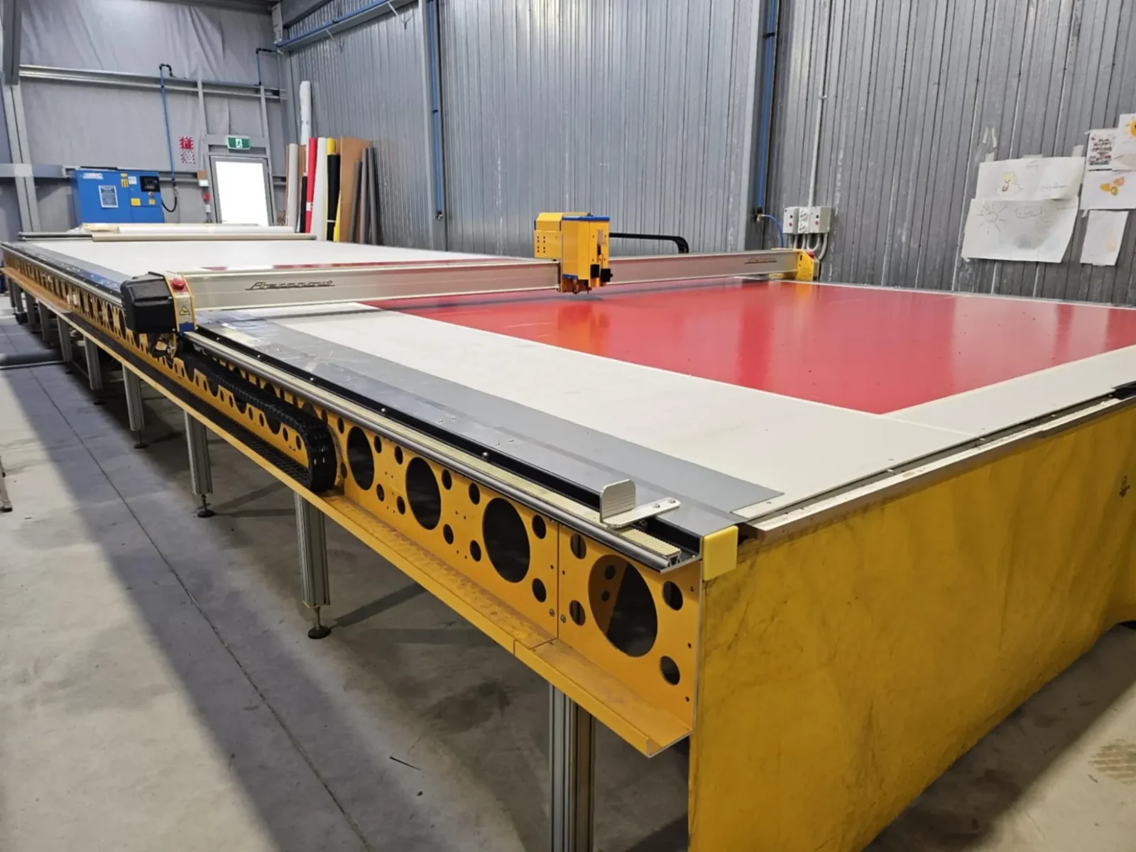 CNC cutting table plotting a red PVC panel in the Canvasland workshop
