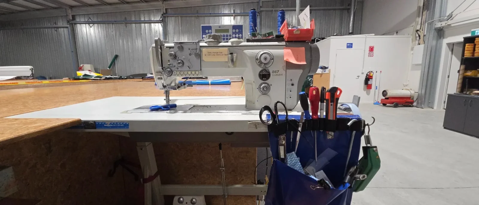 Industrial walking-foot sewing machine on the cutting table in the Levin workshop