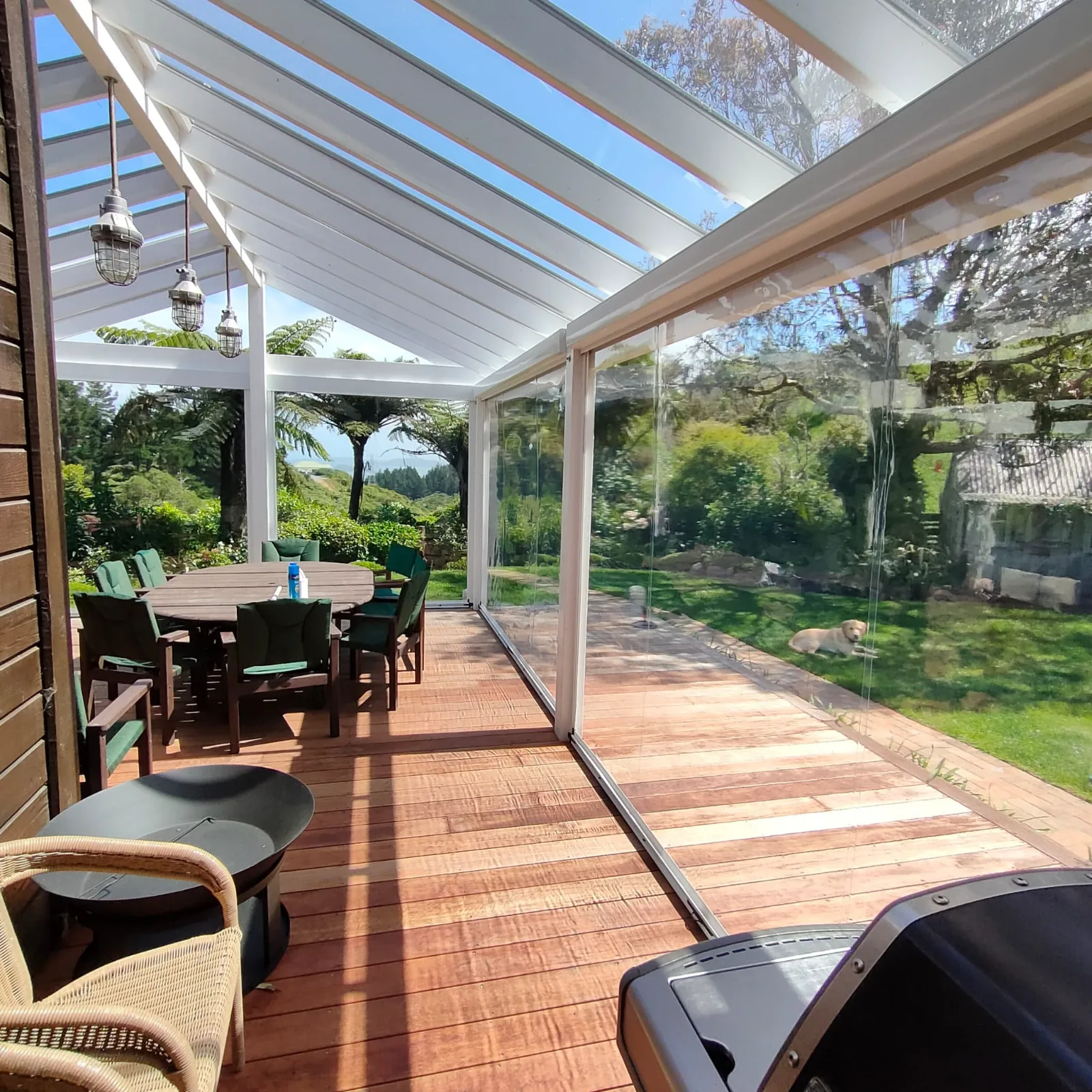 Ziptrak outdoor blinds running the length of a covered timber deck, rolled up to open the room to the garden