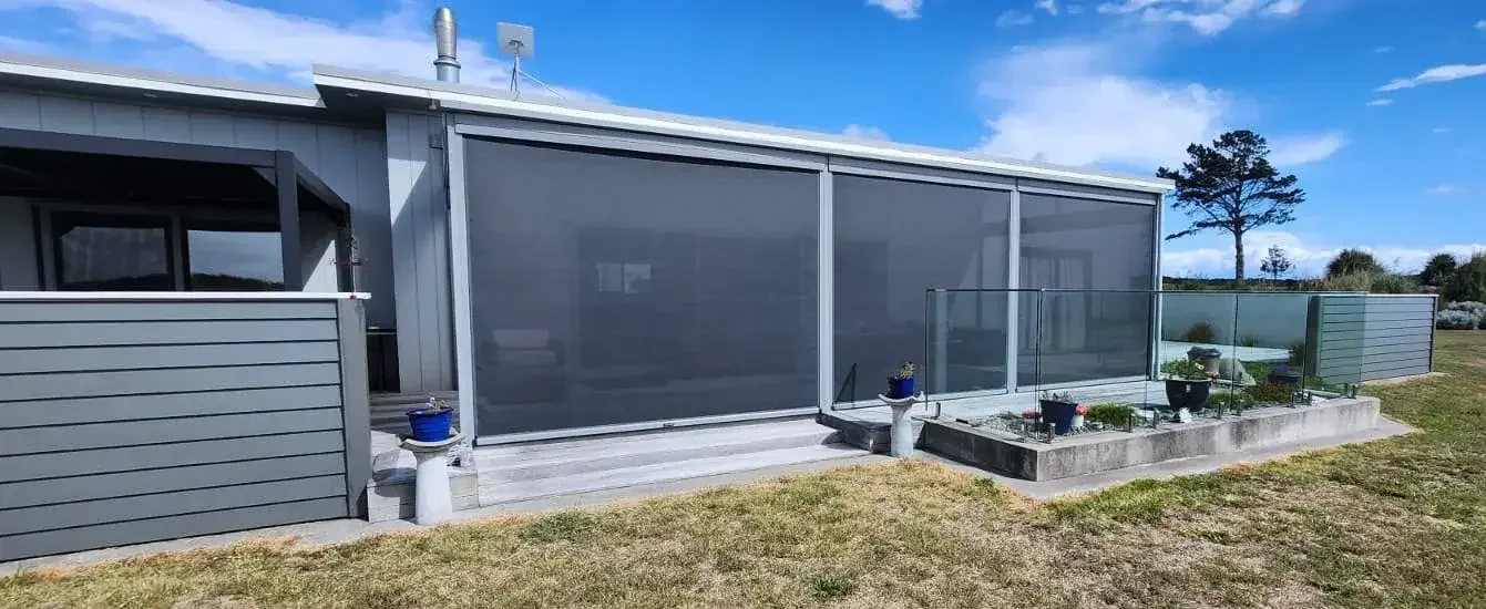 Ziptrak blinds on a coastal home behind a glass balustrade