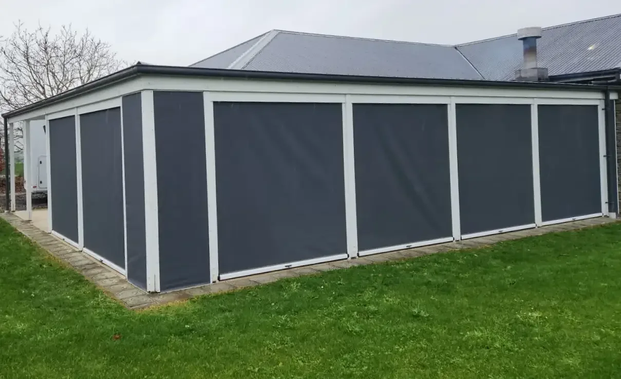 Ziptrak blinds fully lowered across a large outdoor room beside a lawn